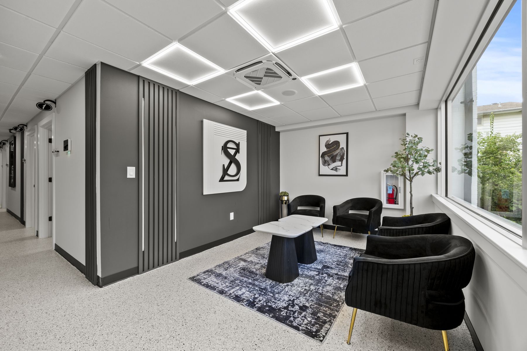 The client lounge with black velvet armchairs, a marble coffee table and the ZS monogram on the wall