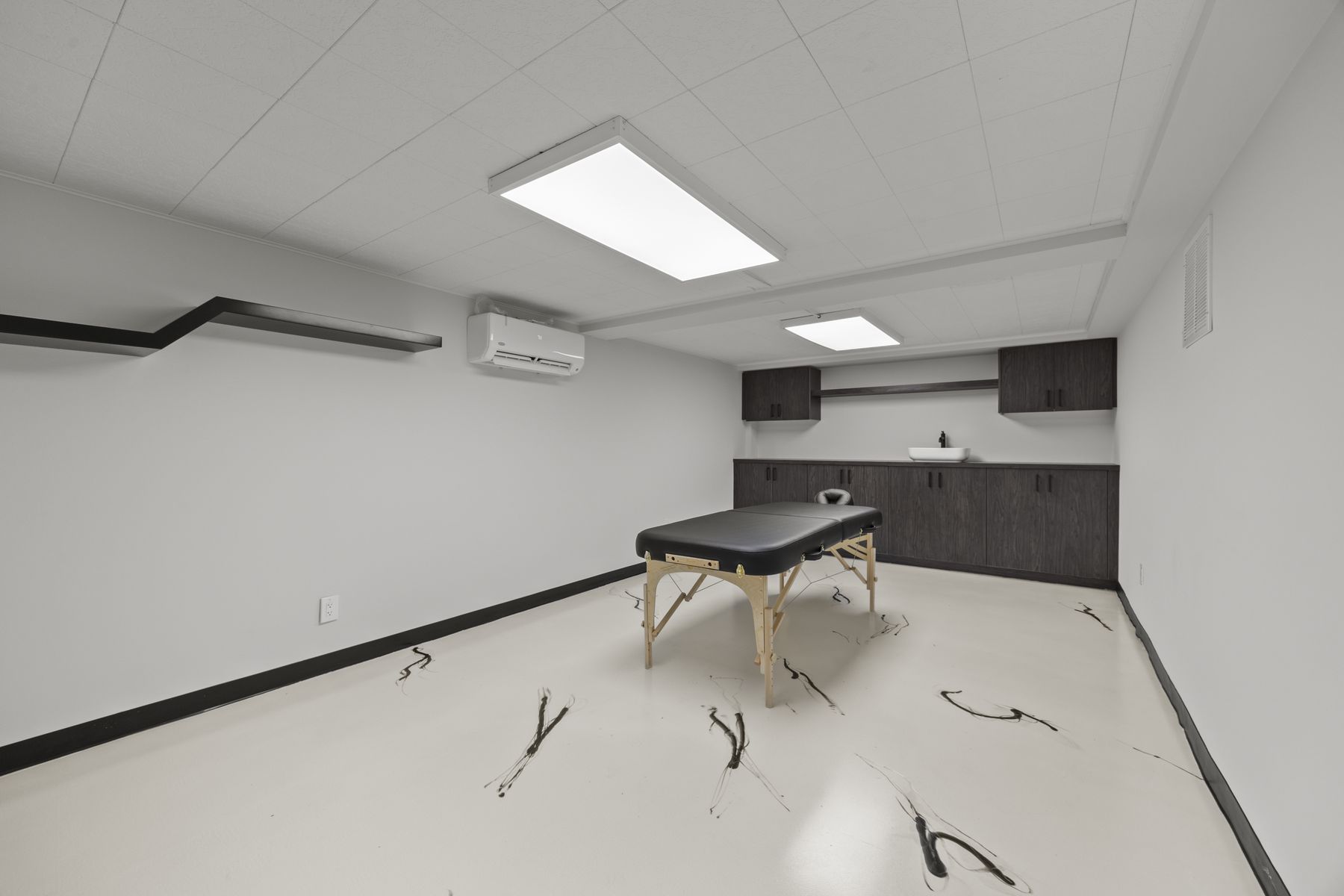 Spa room with a treatment table, sink and cabinets