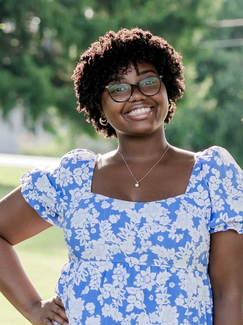 The Beauty Breakroom stylist smiling outdoors in a blue floral top